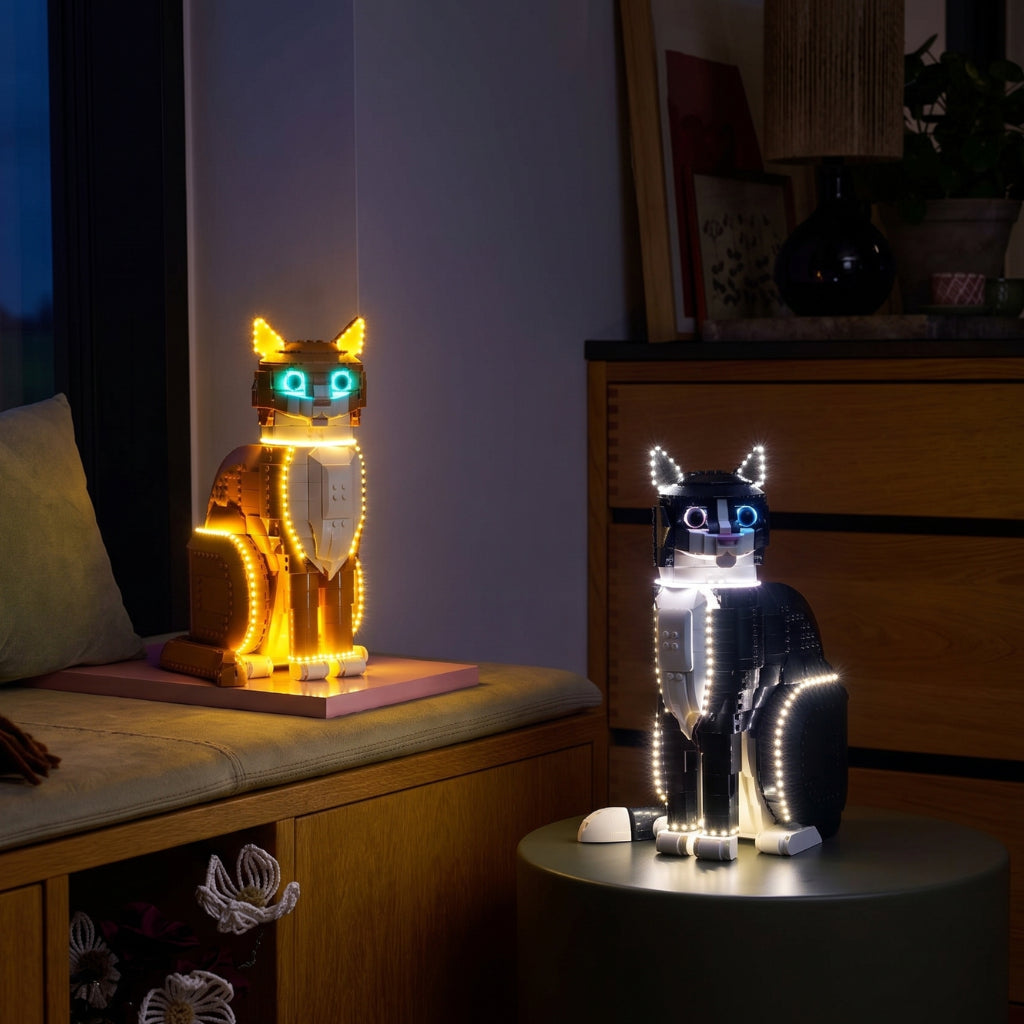 LEGO Ideas 21376 Ginger Cat and 21349 Tuxedo Cat sets glowing with LED lighting kits in a warm home interior