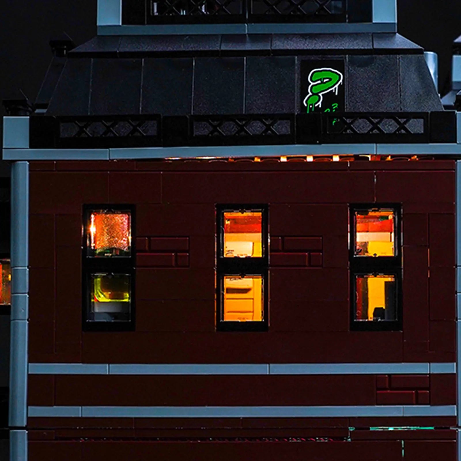 The fully illuminated LEGO Arkham Asylum 76300 stands as a menacing centerpiece in a darkened collector's display.