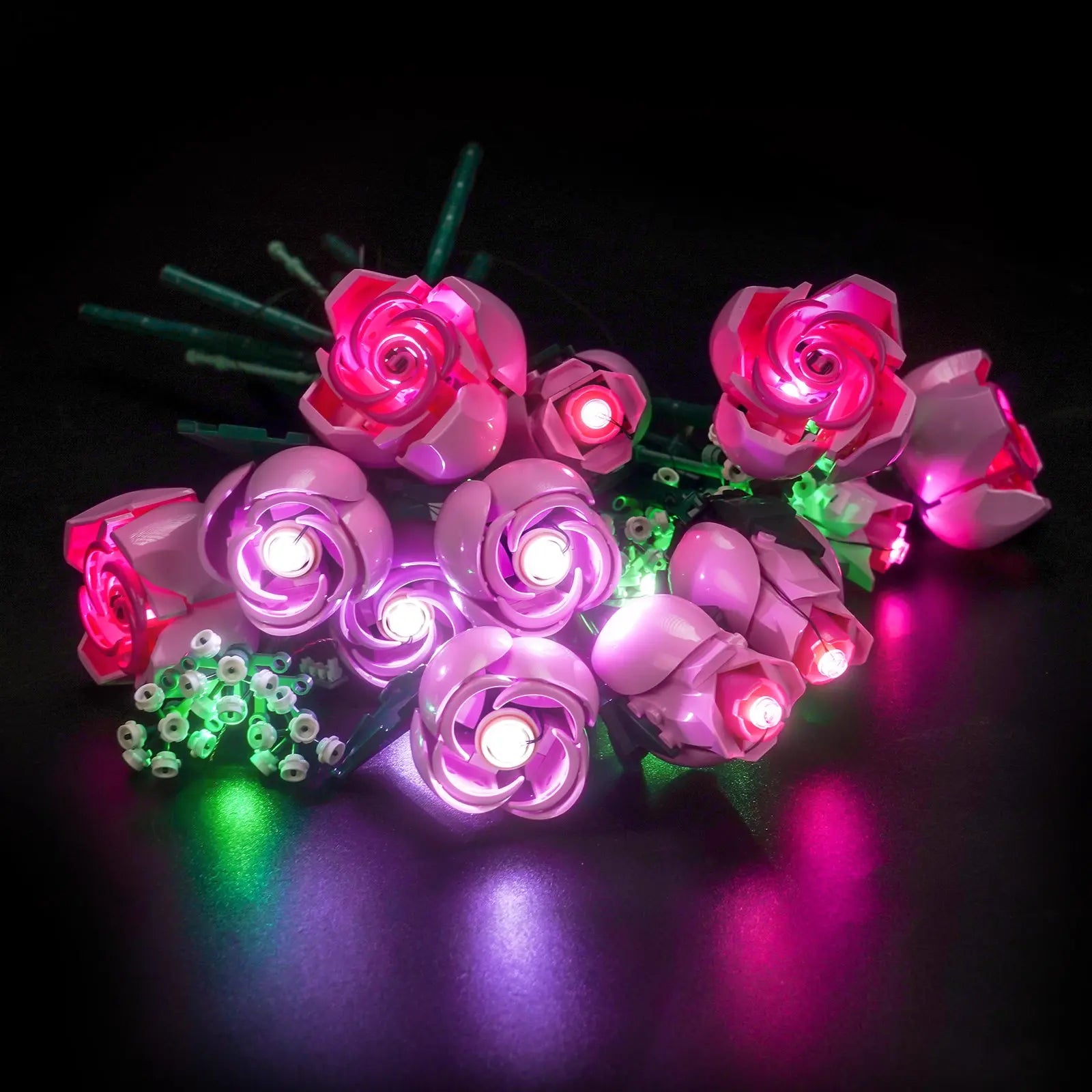 A close-up of a single pink rose from the LEGO 10374 set, with a soft, warm light glowing from within its petals.