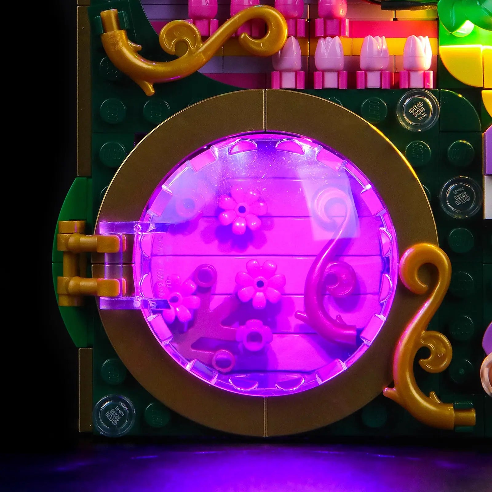 The illuminated LEGO Wicked Wall Art 75685 hanging on a wall, casting a magical green ambient glow in a dark room.