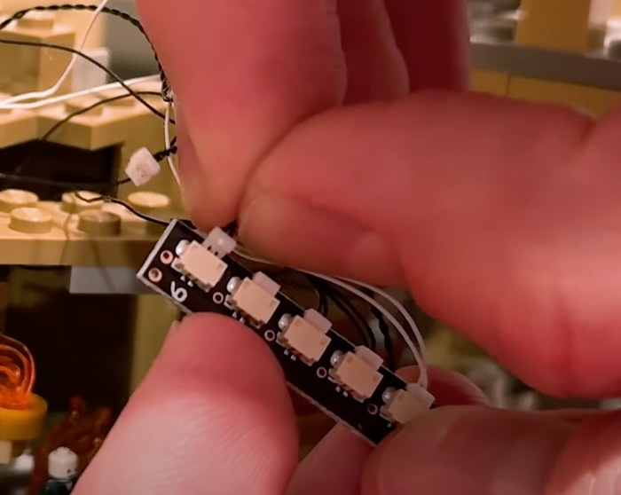 A Bright My Bricks LED strip held between two fingers