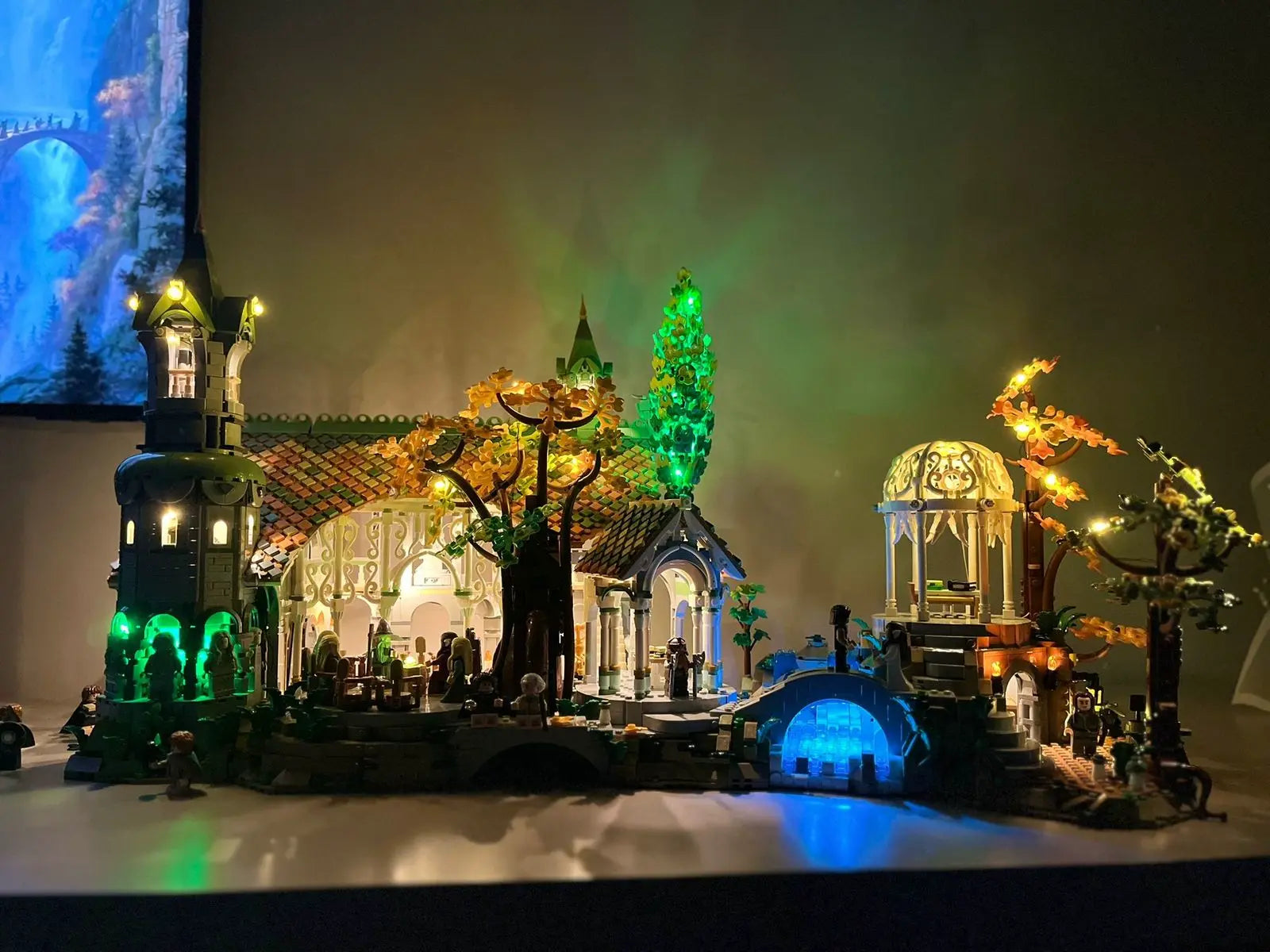 Sumptuous LEGO Icons Lord of the Rings Rivendell (10316) with 6167 pieces featuring custom LED lighting system. The Elven dwelling comes alive with warm golden light in the main buildings, mystical blue illumination in the waterfalls and caves, and green touches lighting the lush vegetation. The golden dragon on the right adds an epic touch to this beautifully illuminated Middle-earth scene.