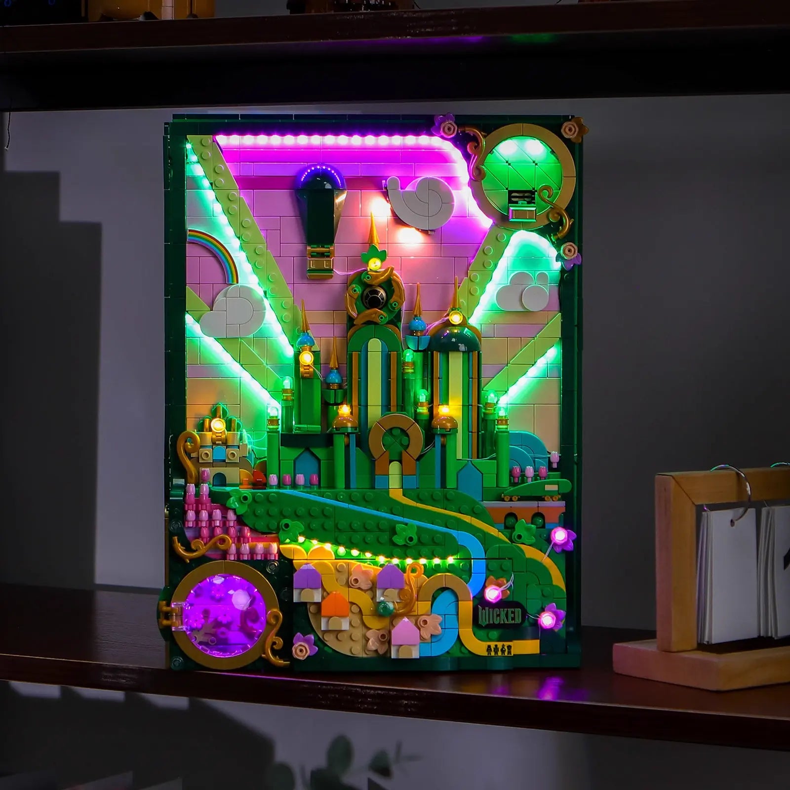 The iconic Yellow Brick Road on the LEGO Wicked 75685 art piece is lit up, guiding the way to the glowing city.