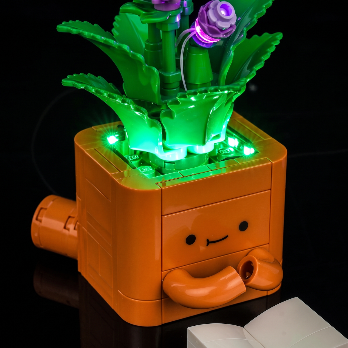 Close-up of the smiling brown pot, green-lit rim and purple buds — LEGO® Cozy Plants #10371