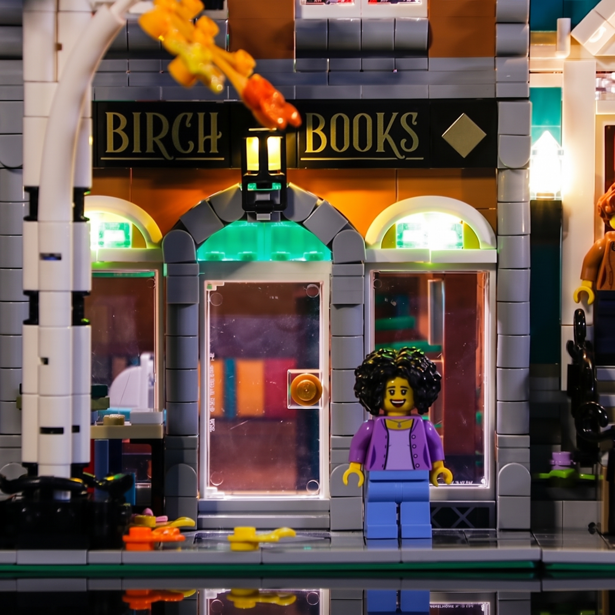 Nahaufnahme des Eingangs von LEGO Buchhandlung 10270 mit Birch-Books-Schild und beleuchteten Bogenfenstern