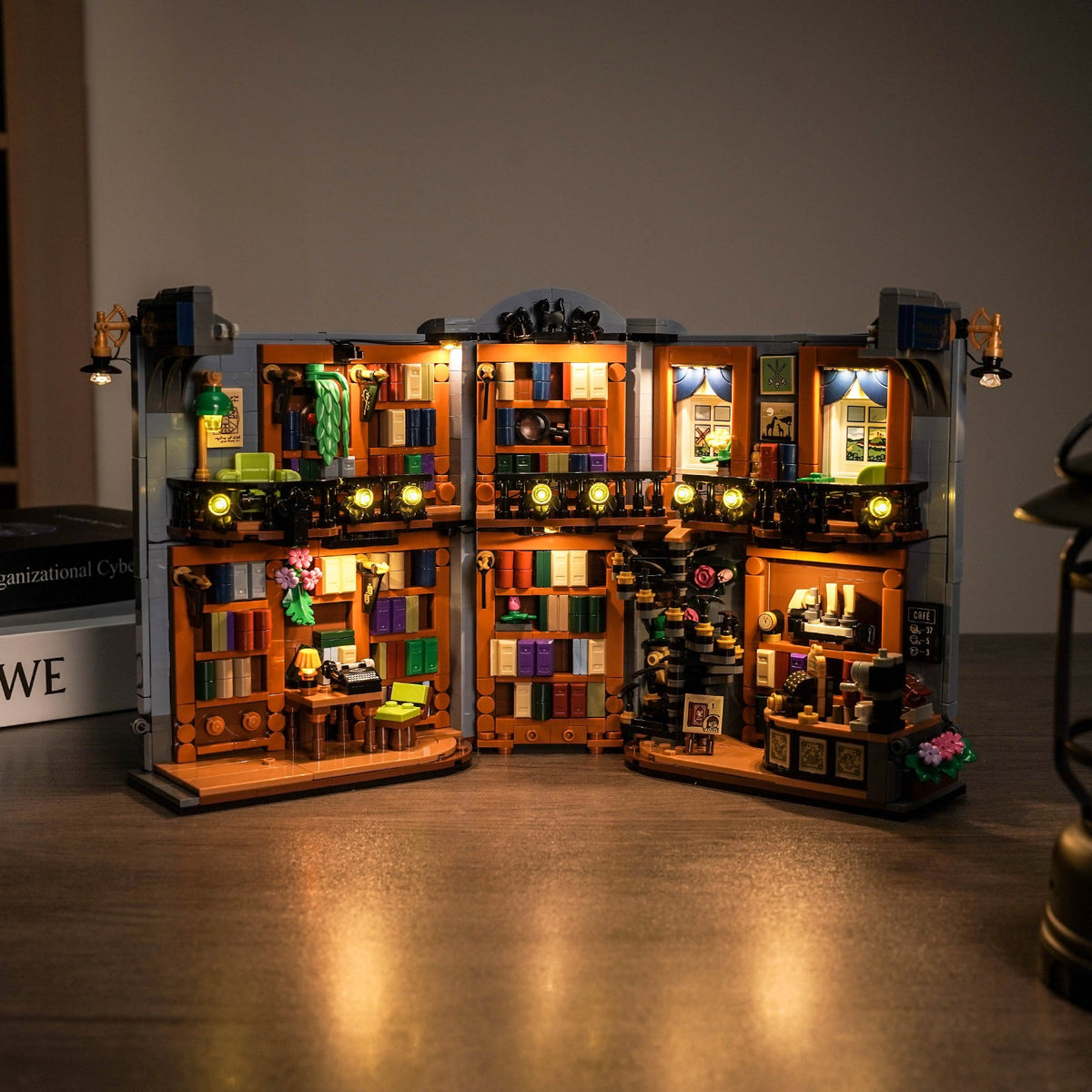 LEGO® La librairie : book nook #11379 ouvert et illuminé montrant bibliothèque, balcon et café dans un intérieur