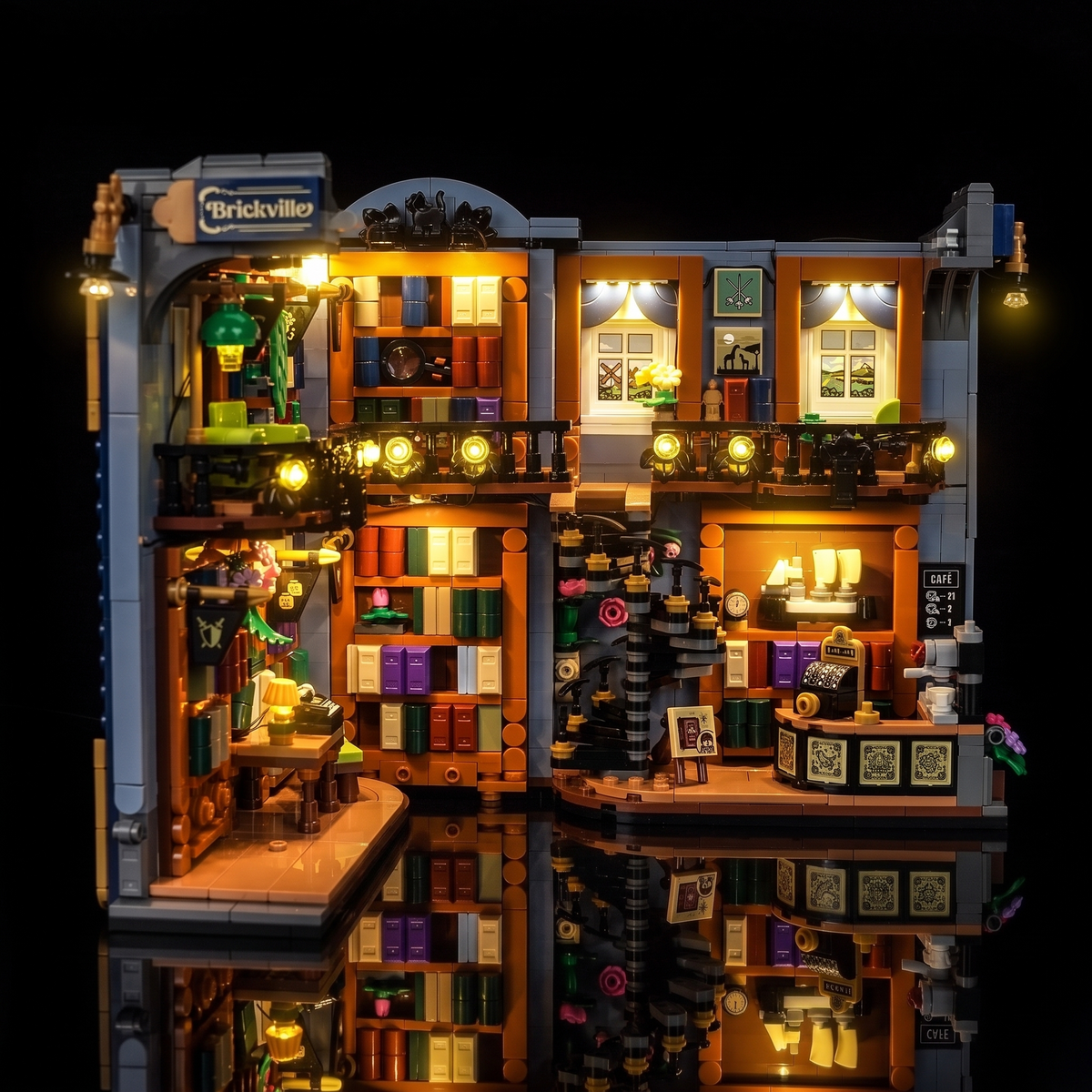 Vue avant droite du LEGO® La librairie : book nook #11379 ouvert avec fenêtres, escalier et café illuminés