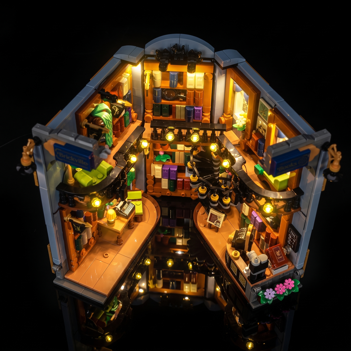 Vue plongeante du LEGO® La librairie : book nook #11379 ouvert avec balcon illuminé et espaces de lecture détaillés
