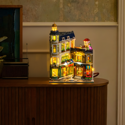LEGO® Icons Einkaufsstraße 11371 mit beleuchteten Schaufenstern auf einem Sideboard