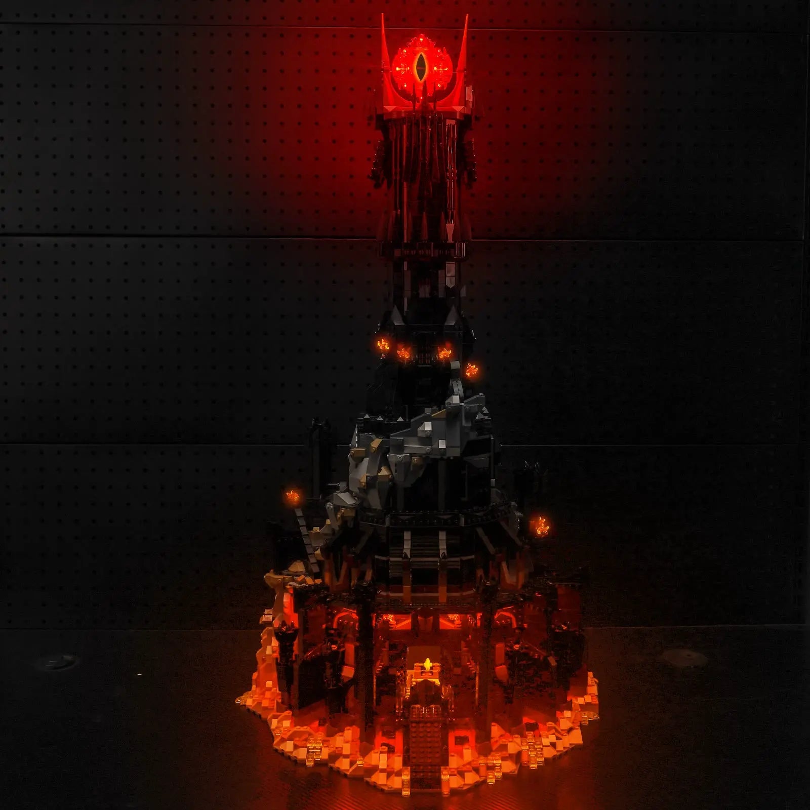 The massive LEGO Icons Barad-dûr 10333 tower, fully illuminated with a menacing, fiery glow by Bright My Bricks.