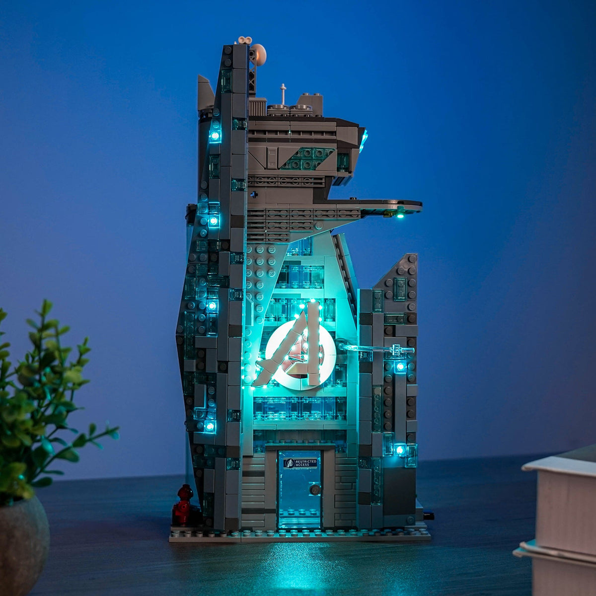 Lifestyle display of the illuminated LEGO® New Avengers Tower #76352 in a dark room