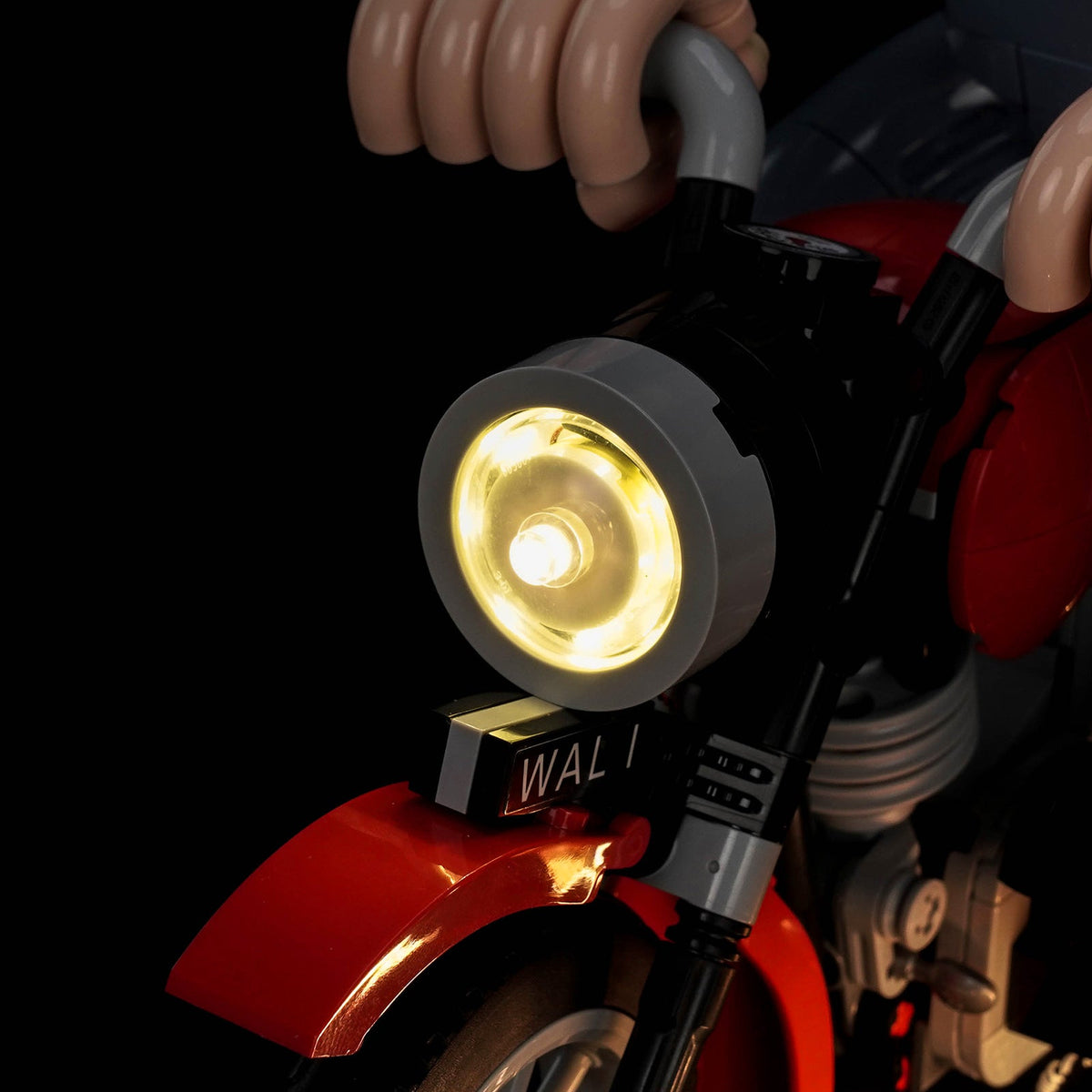 LED-Kit für LEGO Wallace & Gromit 21371, Nahaufnahme des warm leuchtenden Motorradscheinwerfers unter Wallaces Händen