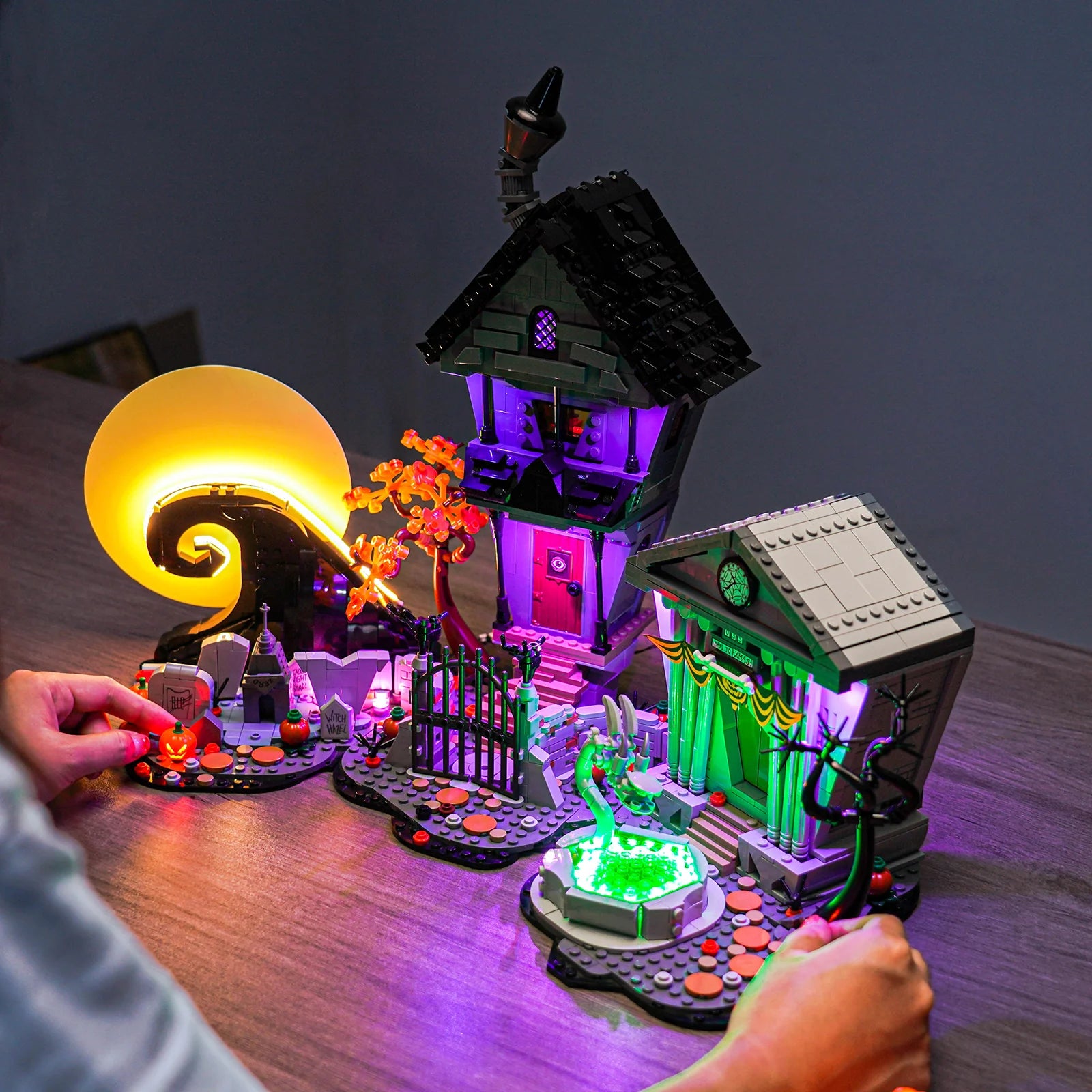 A person holding the illuminated LEGO The Nightmare Before Christmas 21351 set, lit up with the upgraded Bright My Bricks light kit to create a spooky glow.